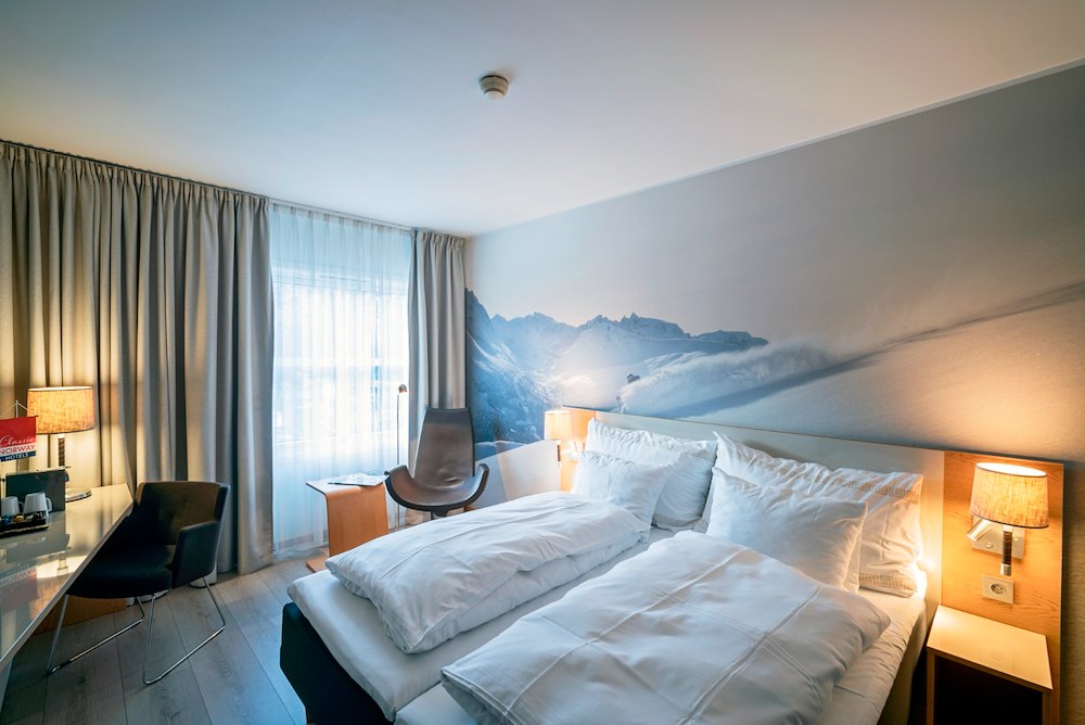 Hotelkamer met tweepersoonsbed en fauteuil bij het raam