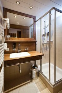 Badkamer met douche, wastafel en spiegel