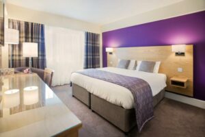 nette hotelkamer met een tweepersoonsbed en een paarse muur