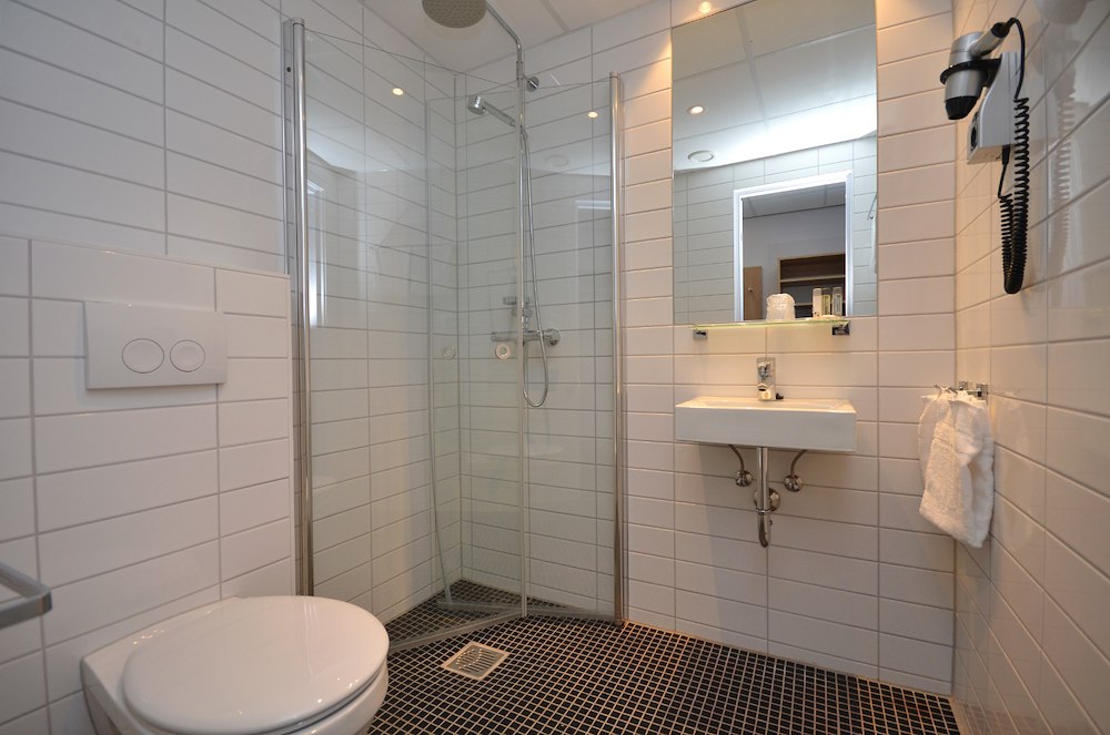 Hotelbadkamer met douche, wastafel en spiegel