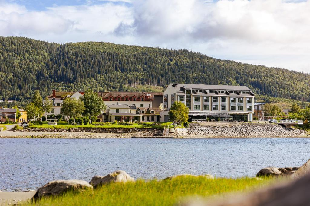 Hotelgebouw aan het water van het fjord met groene heuvels op de achtergrond