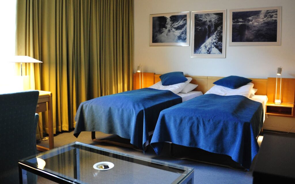 Hotelkamer met twee eenpersoonsbedden, bureau en nachtlampen