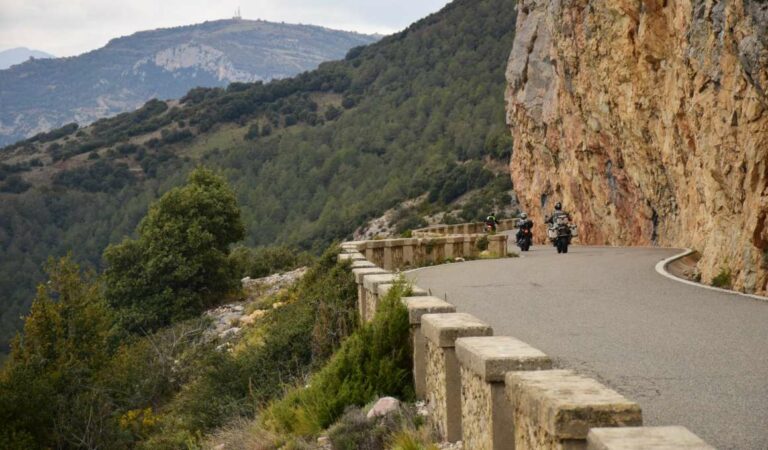 Motorrijders op smalle bergweg langs steile rotswand