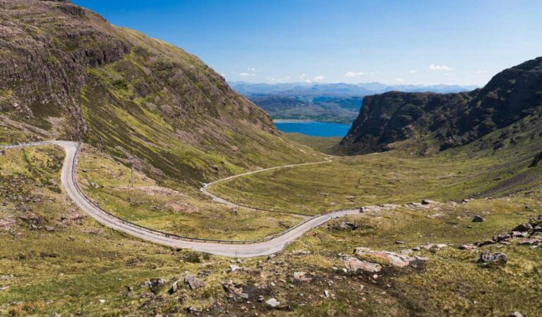 Bergdal met slingerende weg en meer in Schotland
