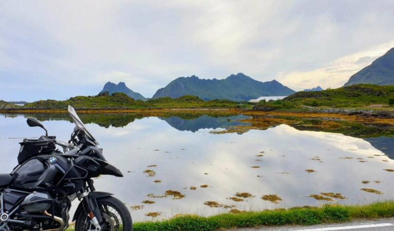 Motorfiets geparkeerd langs stil water met bergen op de achtergrond