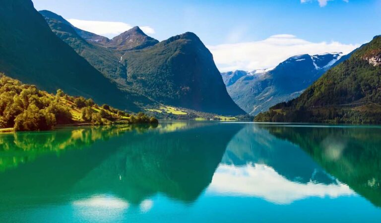 Bergmeer met heldere reflectie van bergen en blauwe lucht