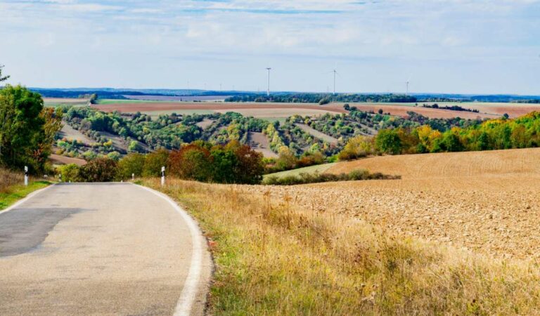 Rustige landweg door glooiend heuvel- en akkerlandschap