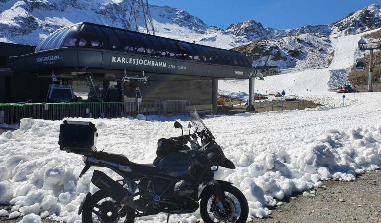 Motorfiets bij sneeuw en bergstation in hooggebergte