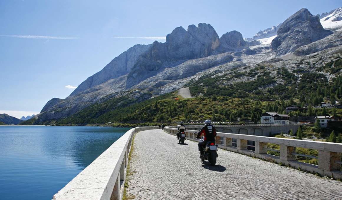 9 essentiële tips voor een geslaagde motorvakantie 11 met de motor rijdend over een stuwdam in de bergen