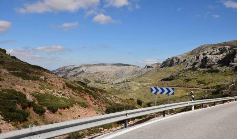 Asfaltweg met vangrail en bochtige route door heuvelachtig landschap