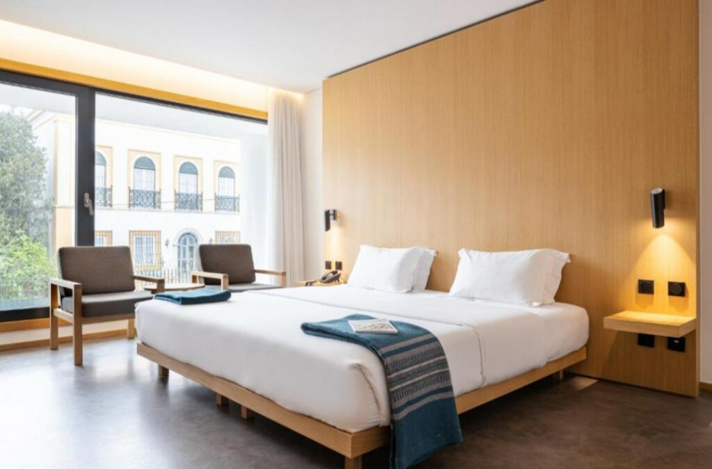Hotelkamer met twee bedden, zitstoelen en groot raam