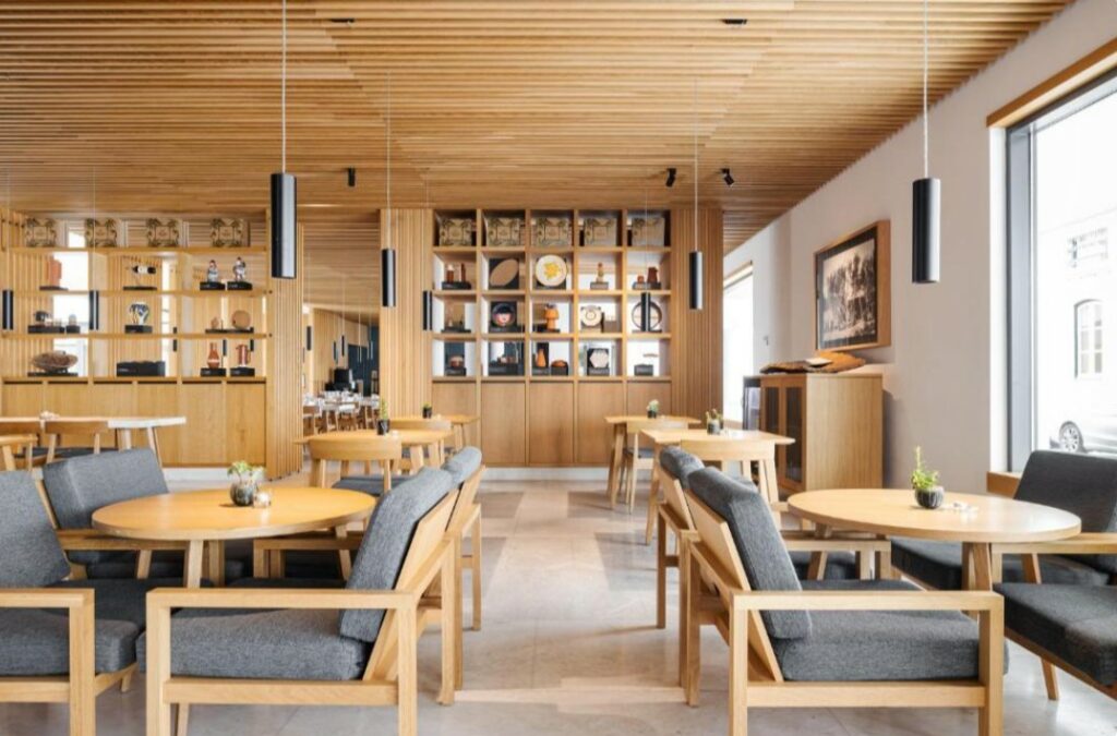 Restaurantinterieur met houten meubels, ronde tafels en grote ramen