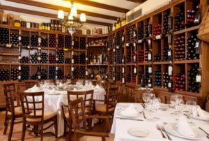 Restaurantinterieur met houten wijnrekken, gedekte tafels en stoelen