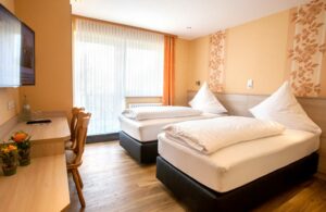 Hotelkamer met twee losse bedden en werkplek