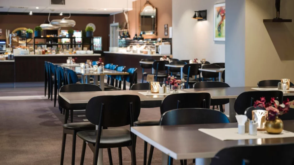 Ontbijtruimte met tafels, stoelen en buffetopstelling
