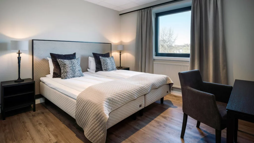 Ruime hotelkamer met twee bedden, bureau en zitstoel