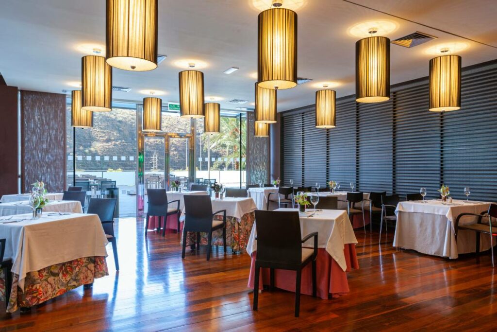 Restaurantzaal met gedekte tafels, houten vloer en hanglampen