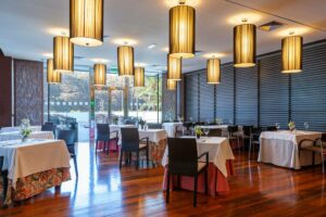 Restaurantzaal met gedekte tafels, houten vloer en hanglampen
