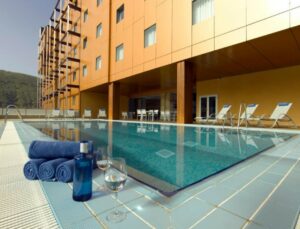 Buitenzwembad met ligbedden naast modern hotelgebouw