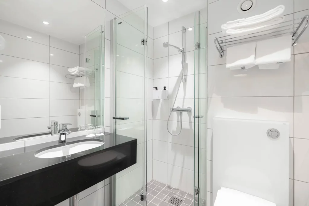 Moderne hotelbadkamer met inloopdouche, wastafel en handdoeken