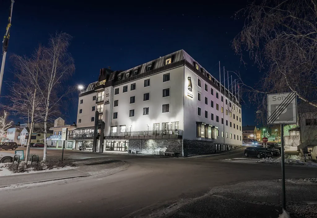 Verlicht hotelgebouw in de avond aan een rustige straat