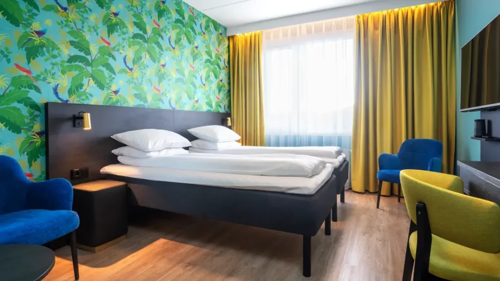 Hotelkamer met groot bed, fauteuils en kleurrijke wand