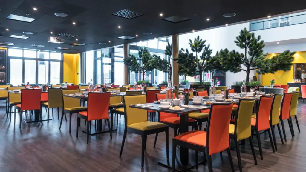 Ruim restaurant met lange tafels en kleurrijke stoelen
