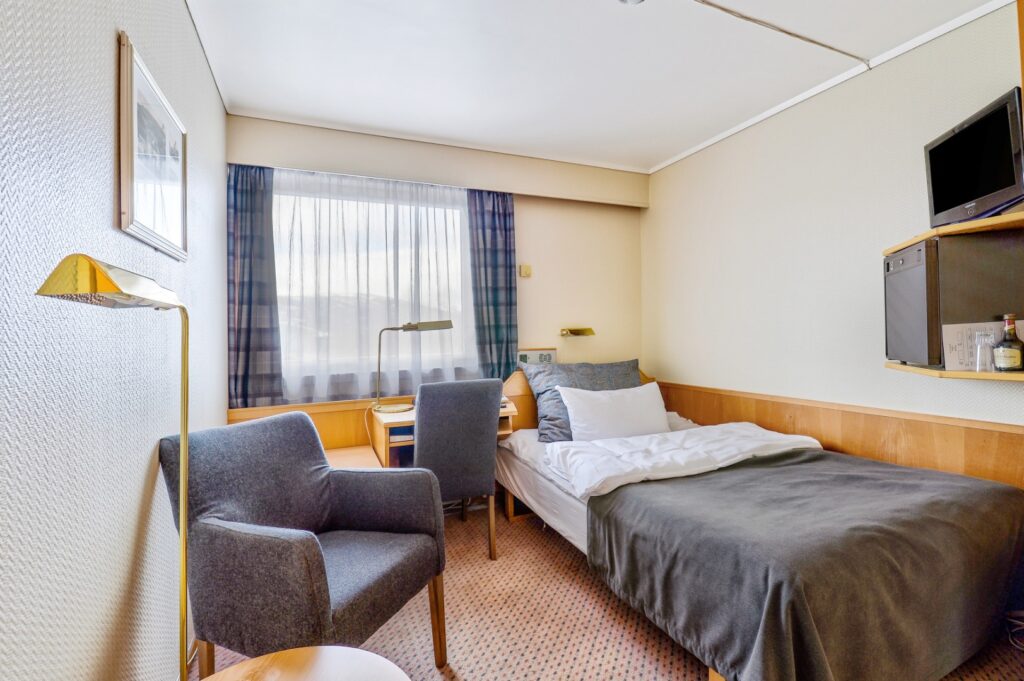Eenvoudige hotelkamer met eenpersoonsbed en zithoek