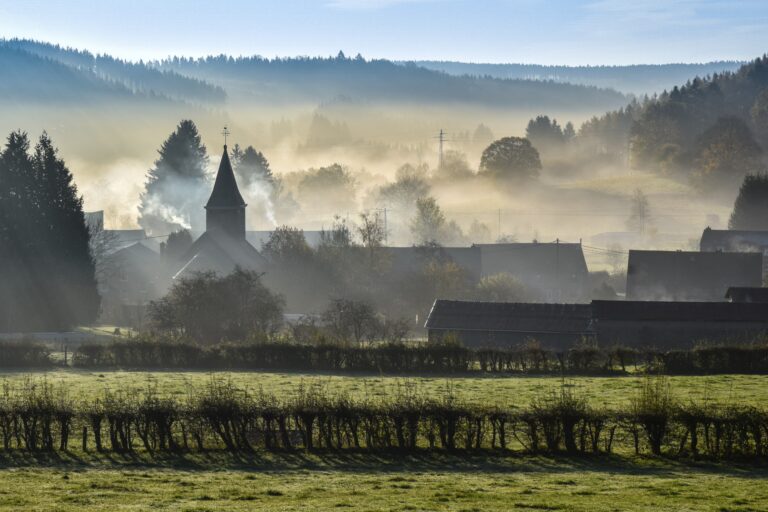 dorp met kerk in mistig dal bij zonsopkomst