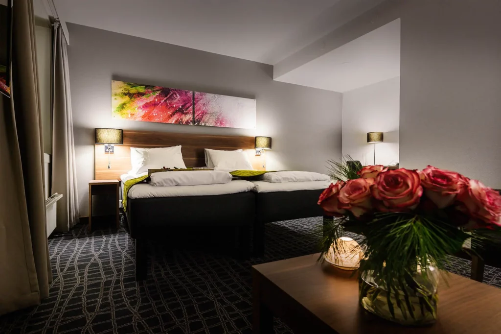 Gezellige hotelkamer met twee bedden en bloemstuk op tafel