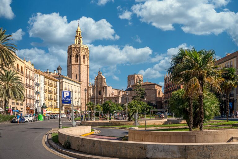 Stadsplein in Valencia met kerk, palmbomen en omliggende bebouwing