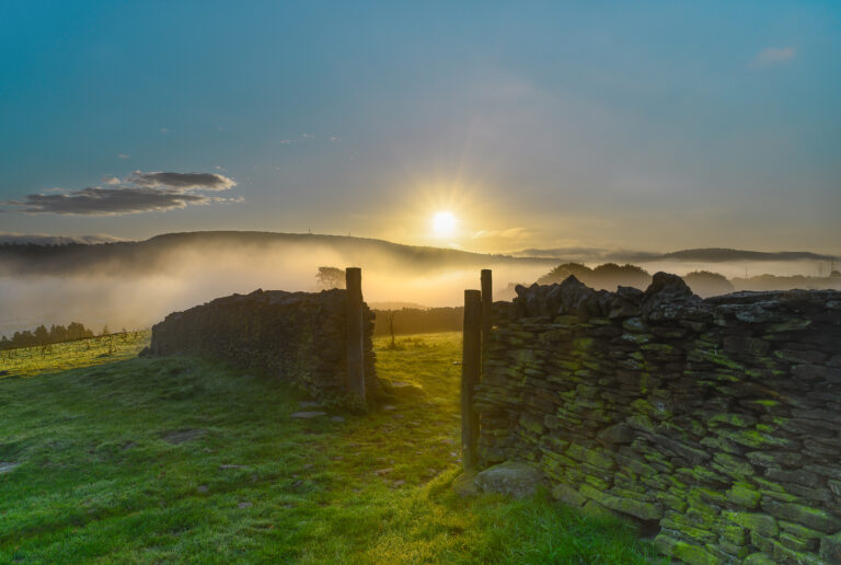 Stenen muur in landschap bij zonsopkomst